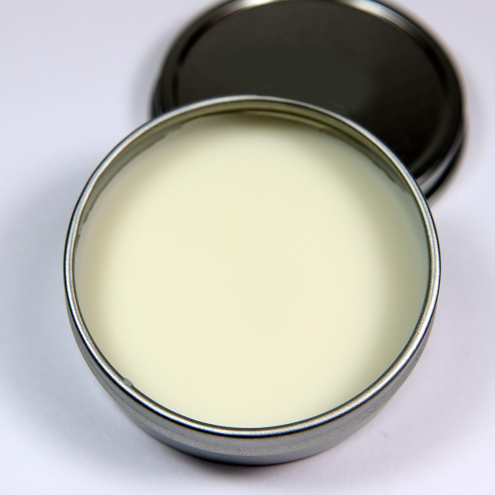 Small tin of cannabis balm on a white surface.