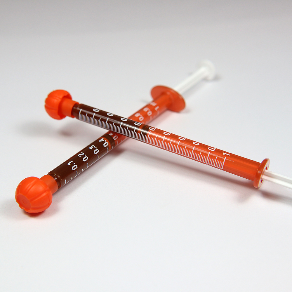 Two cannabis concentrate syringes on a white background.