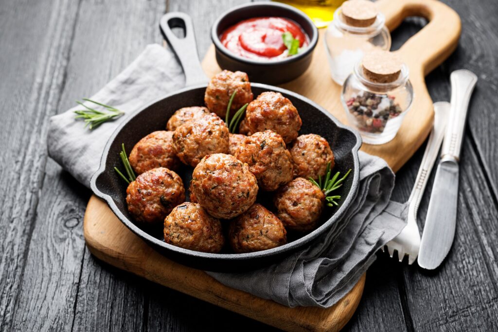 Meatballs in a cast iron pan with herbs and tomato sauce